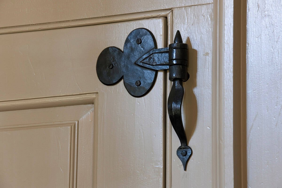 Close-up of hand-forged iron door handle with spade finial on painted cream door