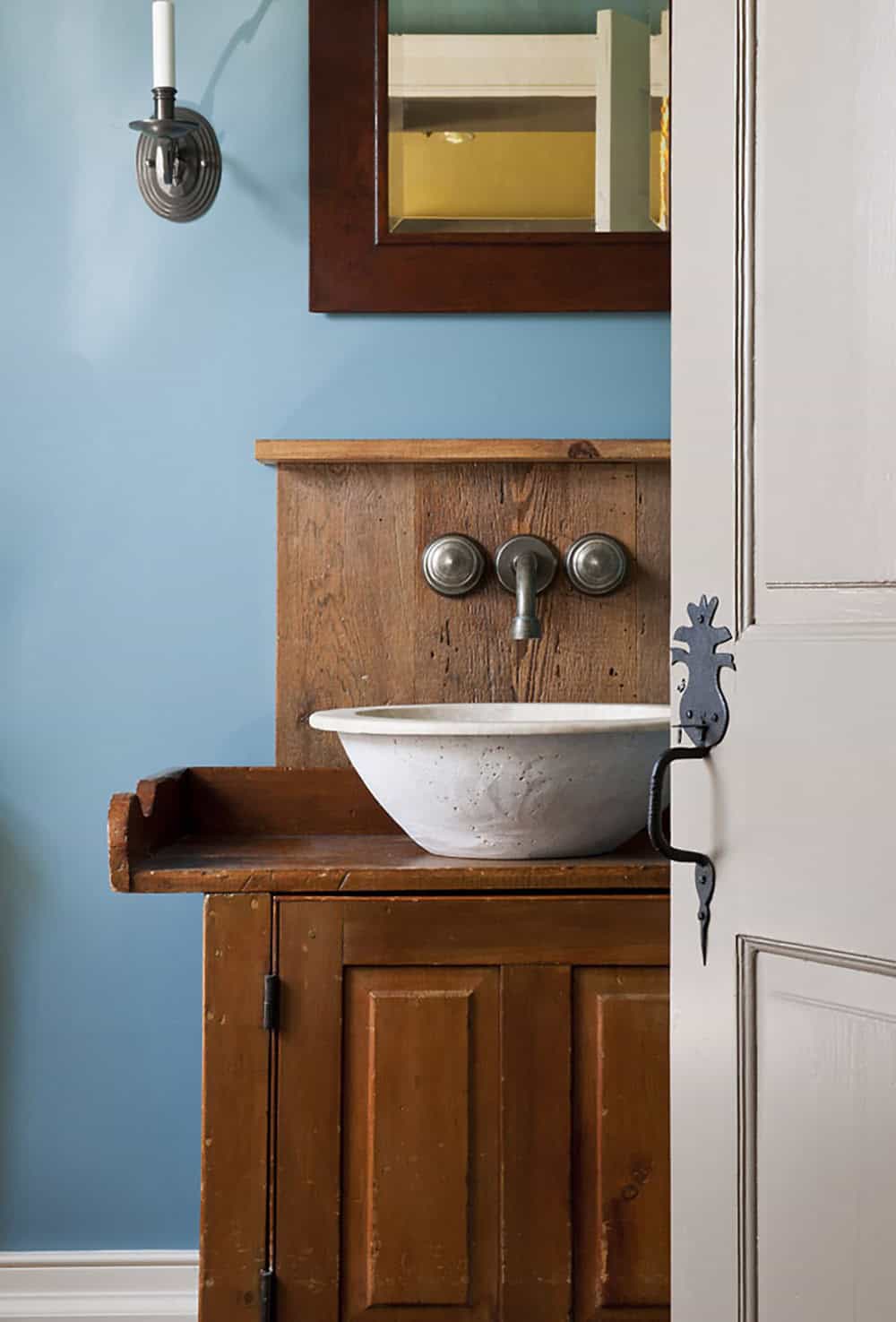 Powder room vanity with vessel sink on antique pine cabinet, pewter wall faucet, and blue painted walls