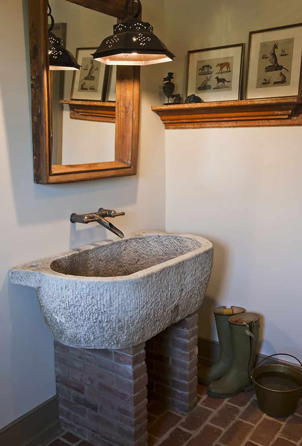 Rustic mudroom with carved stone trough sink on brick pedestal, punched tin pendant, and wellington boots