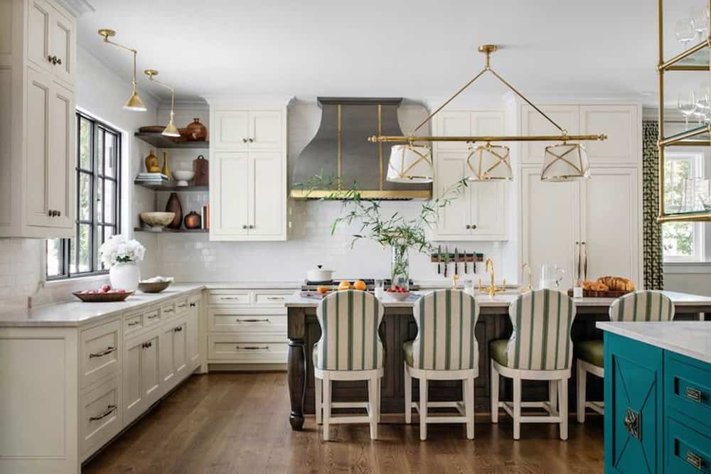 Kitchen with cream cabinetry, dark wood island, striped barstools, and brass pendant lights
