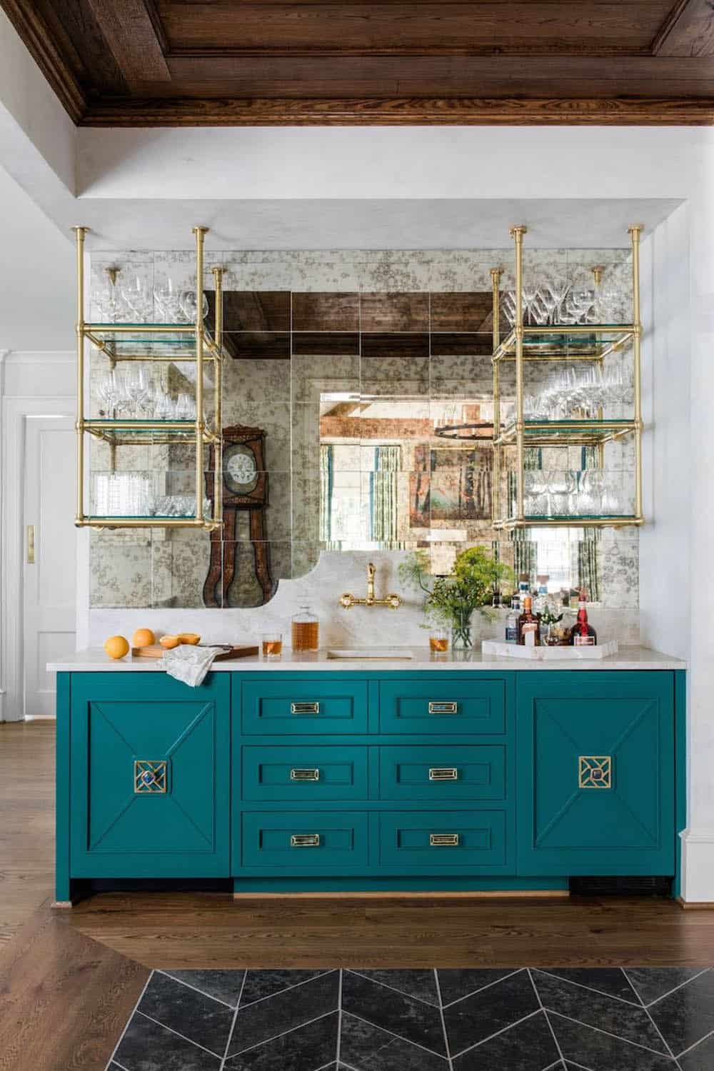 Teal butler's pantry bar with antique mirrored tile backsplash and brass glass shelving