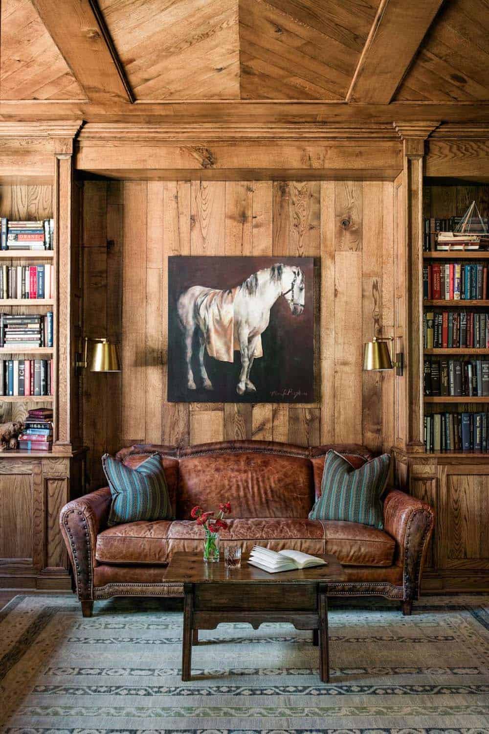 Wood-paneled library with leather chesterfield sofa, bookshelves, and equestrian painting