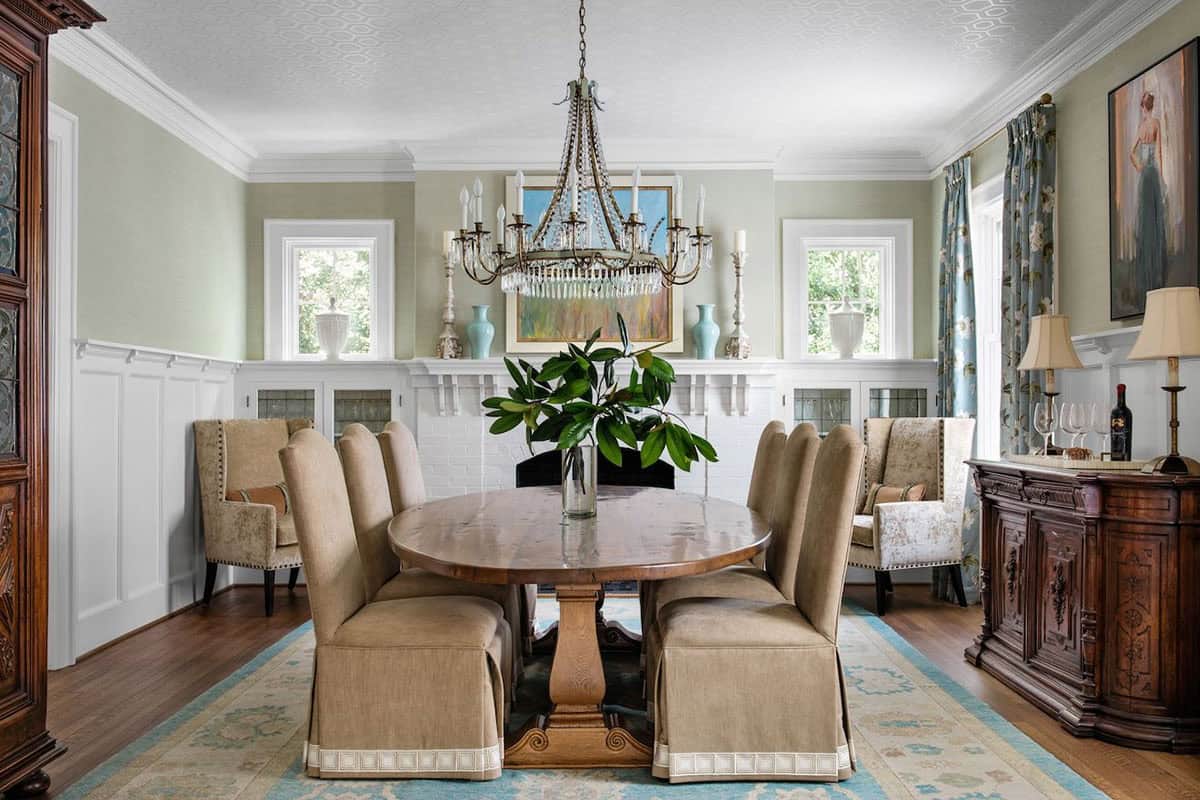 Formal dining room with sage green walls, wainscoting, and crystal chandelier