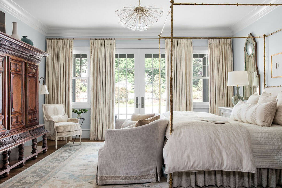 Primary bedroom with brass four-poster bed, French doors, and neutral linen drapery