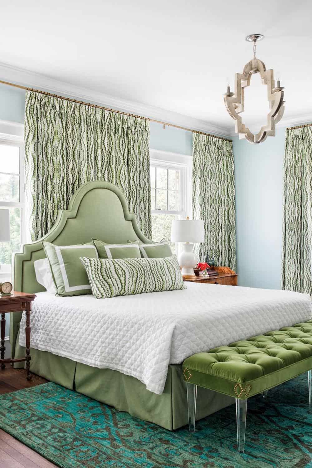 Guest bedroom with sage green upholstered headboard and bold botanical print curtains