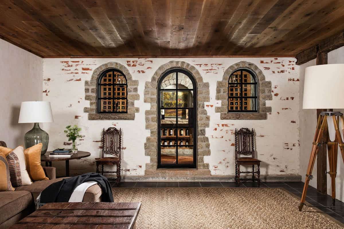 Lower level lounge with whitewashed brick wall and arched wine cellar entry