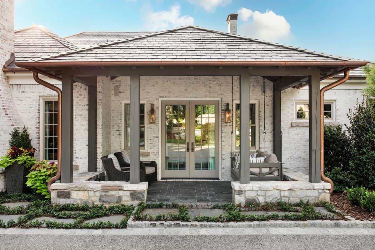 Pool house entry porch with copper gutters, hanging porch swing, and gas lanterns