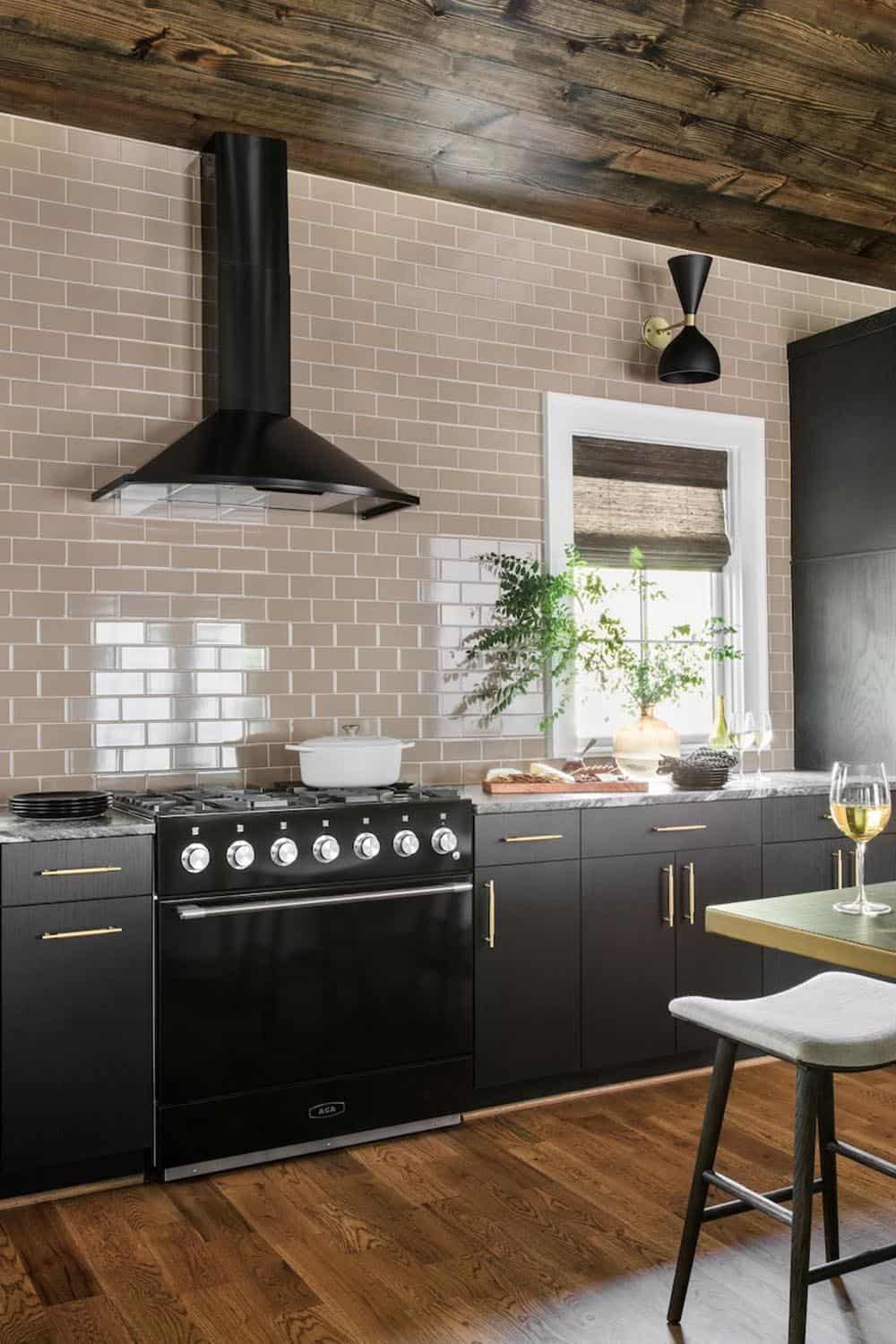 Pool house kitchen with black AGA range, taupe subway tile backsplash, and dark cabinetry