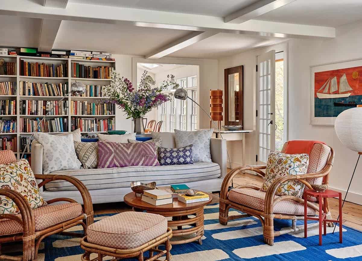 Cozy family room with floor-to-ceiling bookshelves, rattan chairs, linen sofa, colorful pillows, and blue striped rug