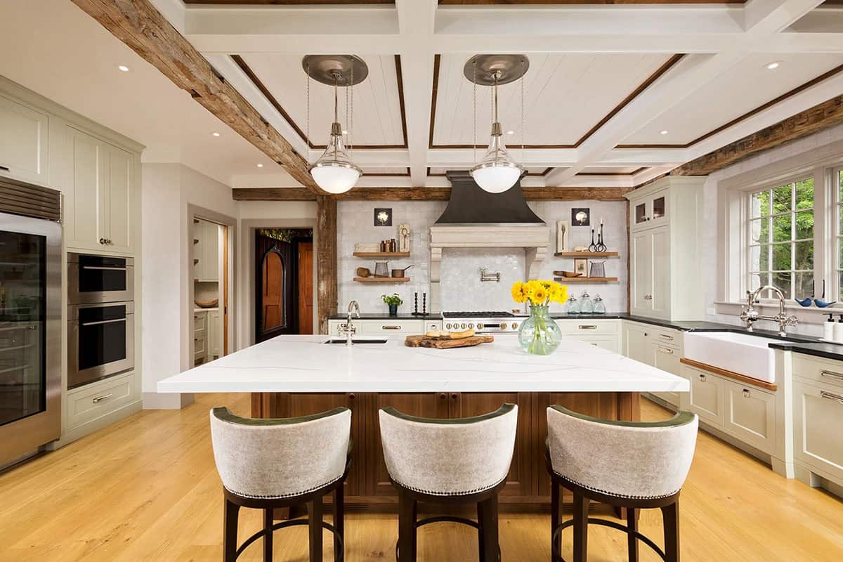 Large farmhouse kitchen with white marble island, sage cabinetry, glass pendant lights, and farmhouse sink