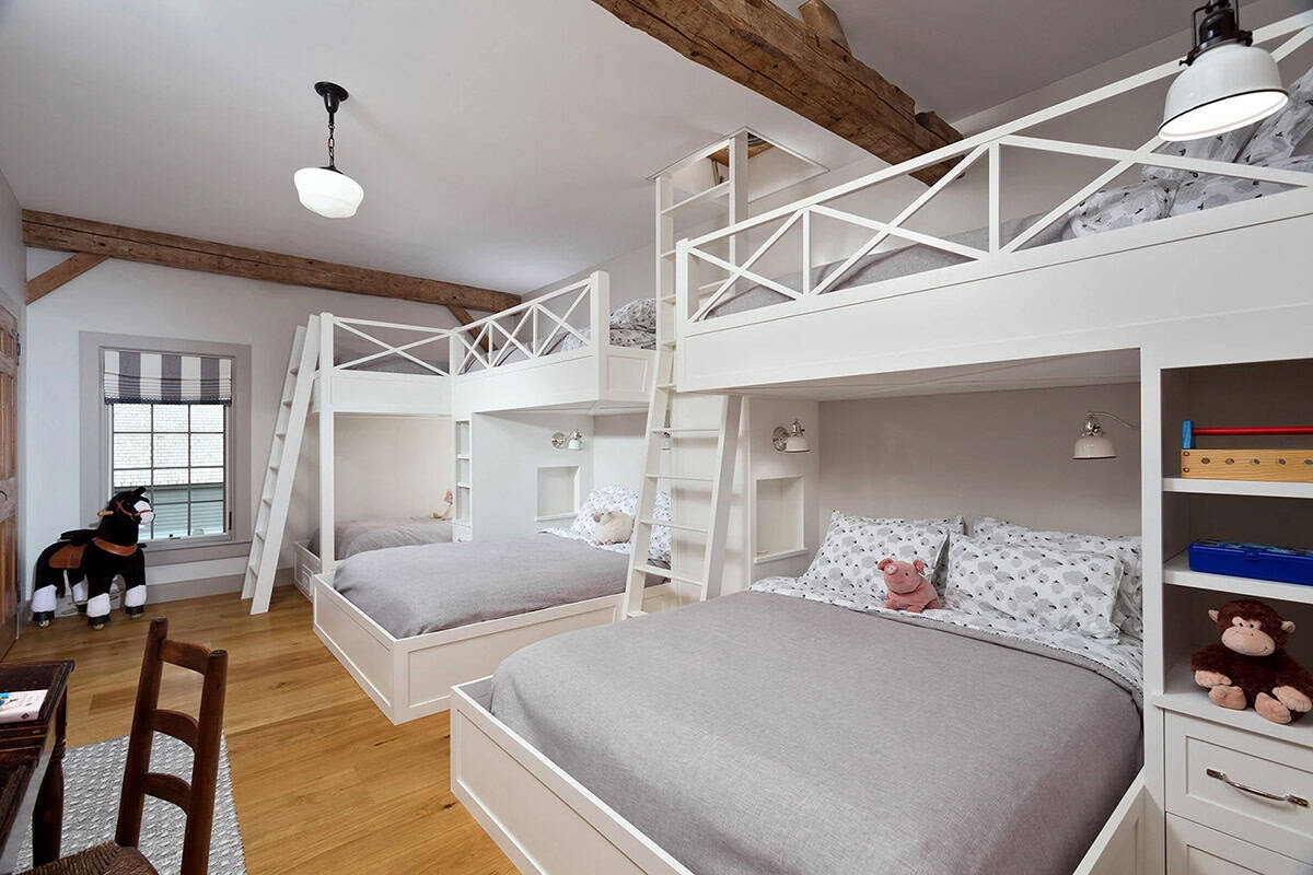 Children's bunk room with four built-in white loft beds, exposed timber beams, and hardwood floors