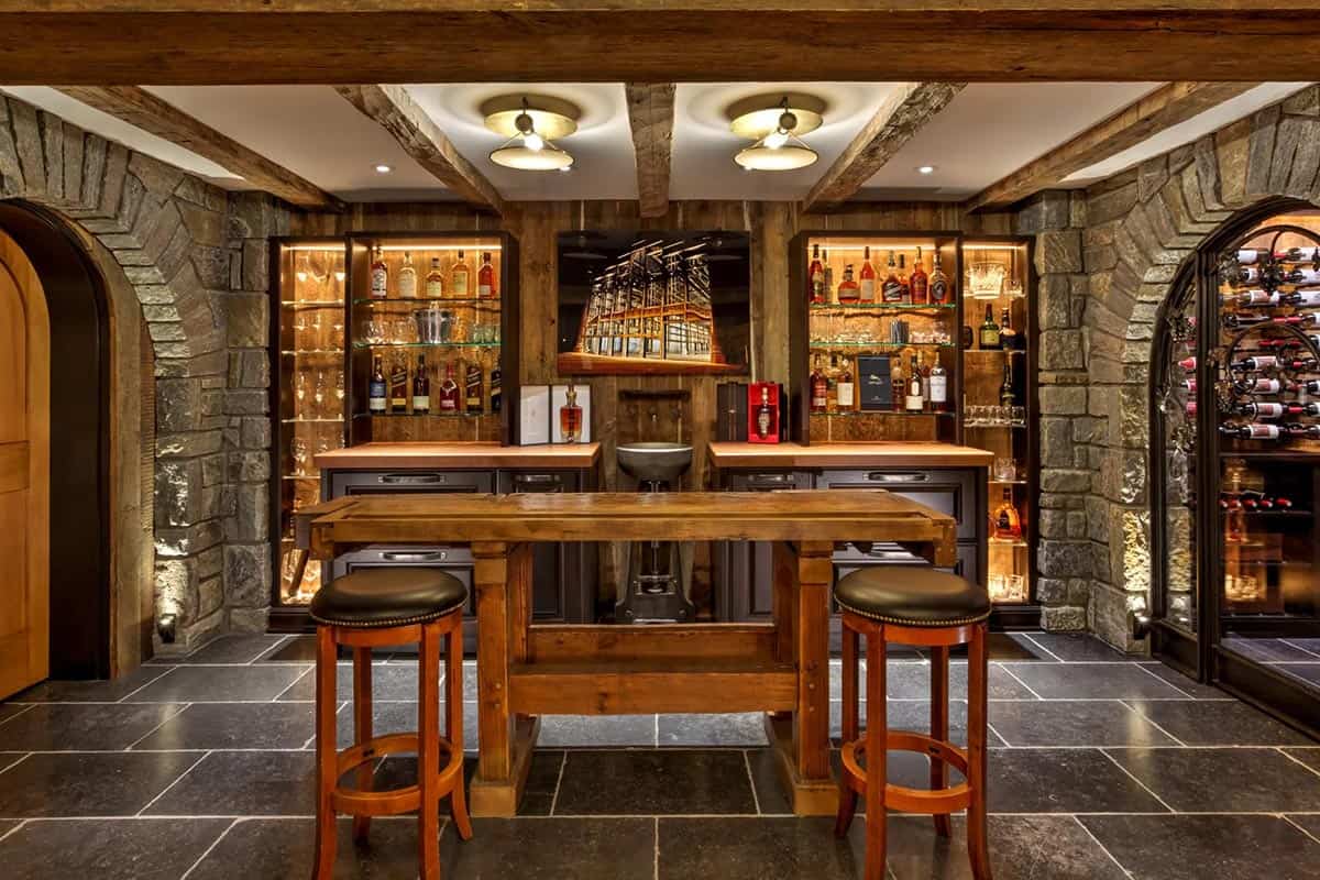 Stone wine cellar and whiskey bar with reclaimed wood shelving, slate tile floor, and arched stone doorways