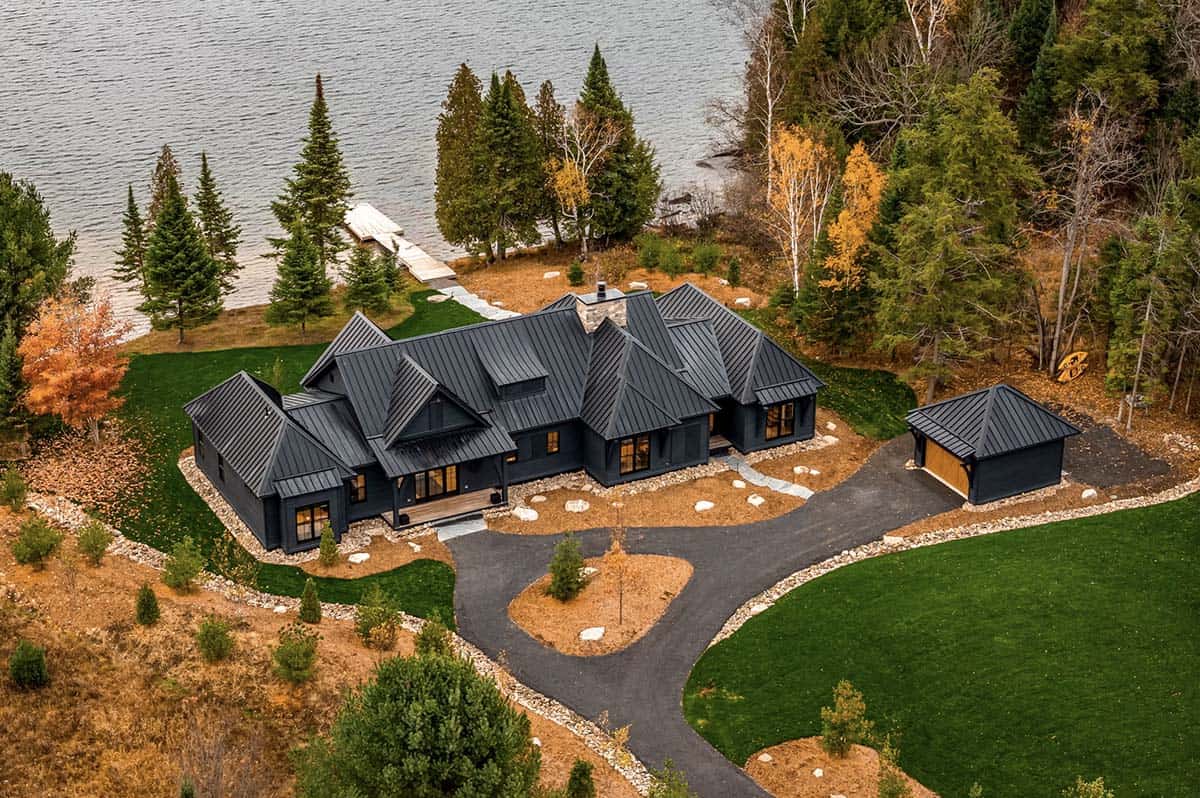 Aerial view of lake house with stone pathway steps and large glass sliding doors at twilight