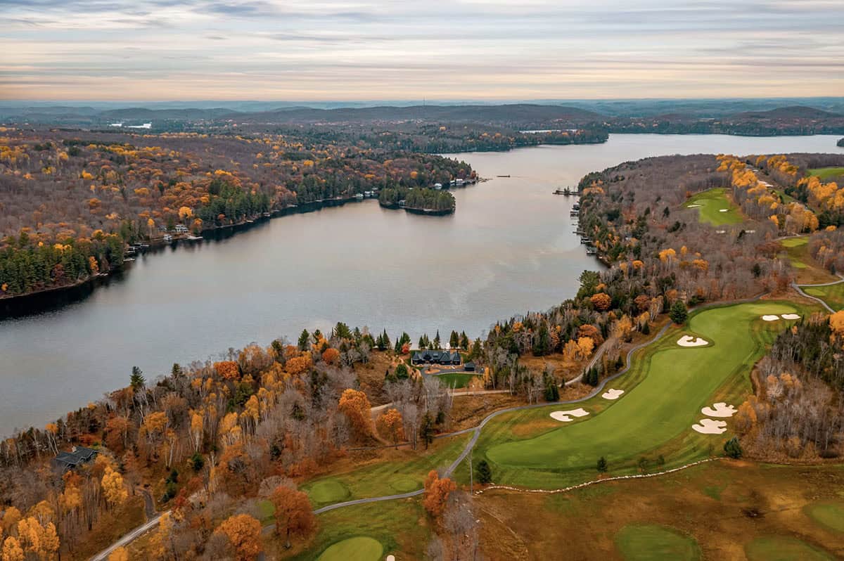 Top-down aerial showing black metal roof layout of cottage with dock extending into lake