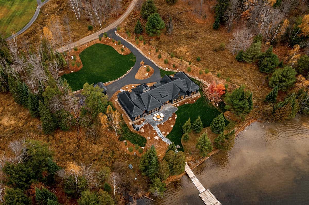 High aerial view of black cottage on lakefront with golf course fairways in background