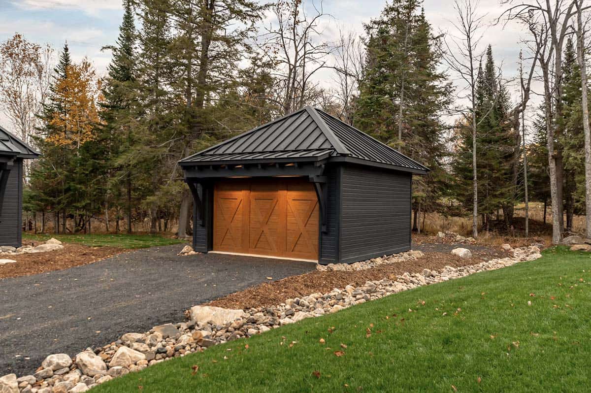Detached black garage with warm cedar barn-style doors and hip metal roof