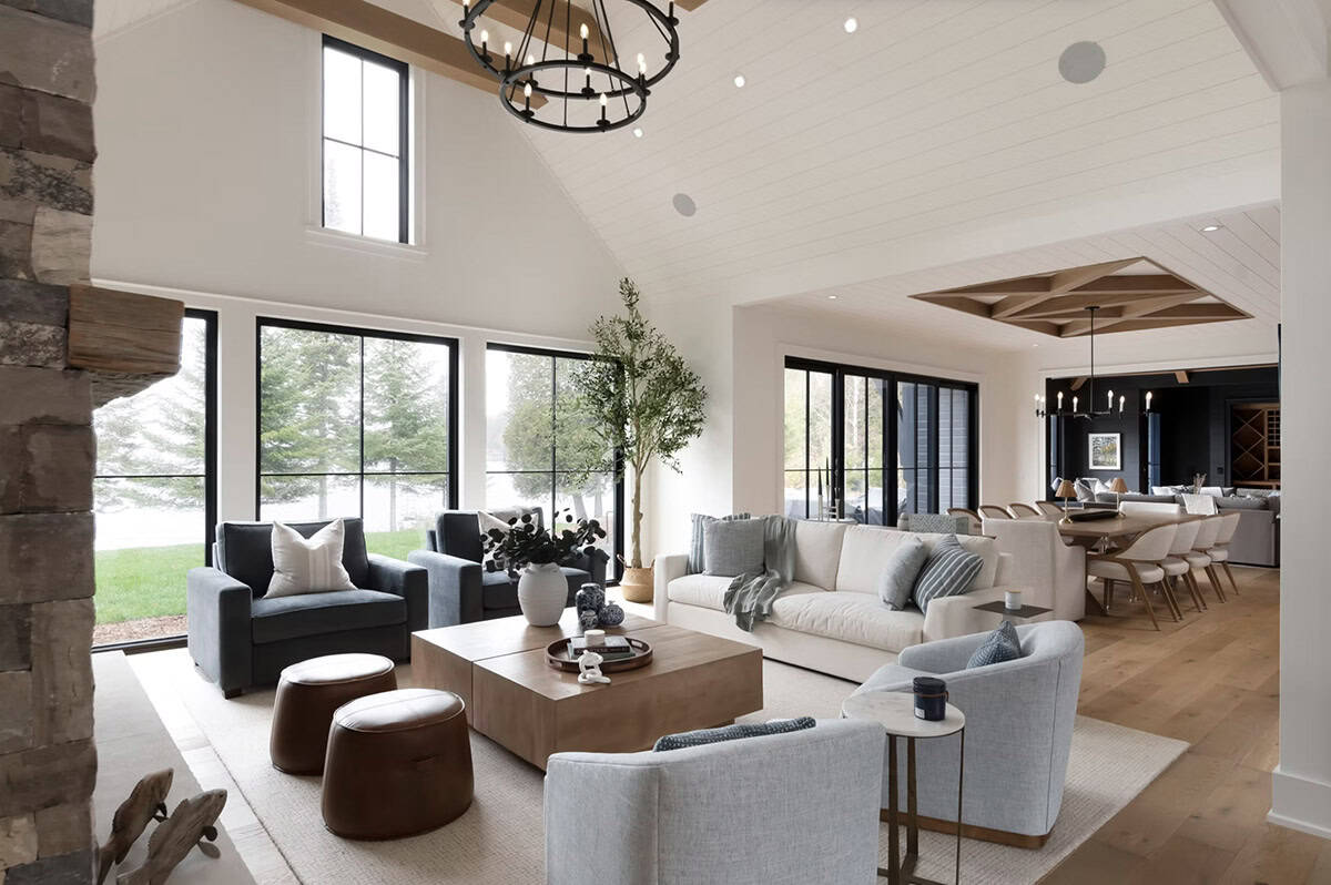 Open-plan living and dining area with vaulted ceiling, black chandelier, and glimpse into kitchen and wine room
