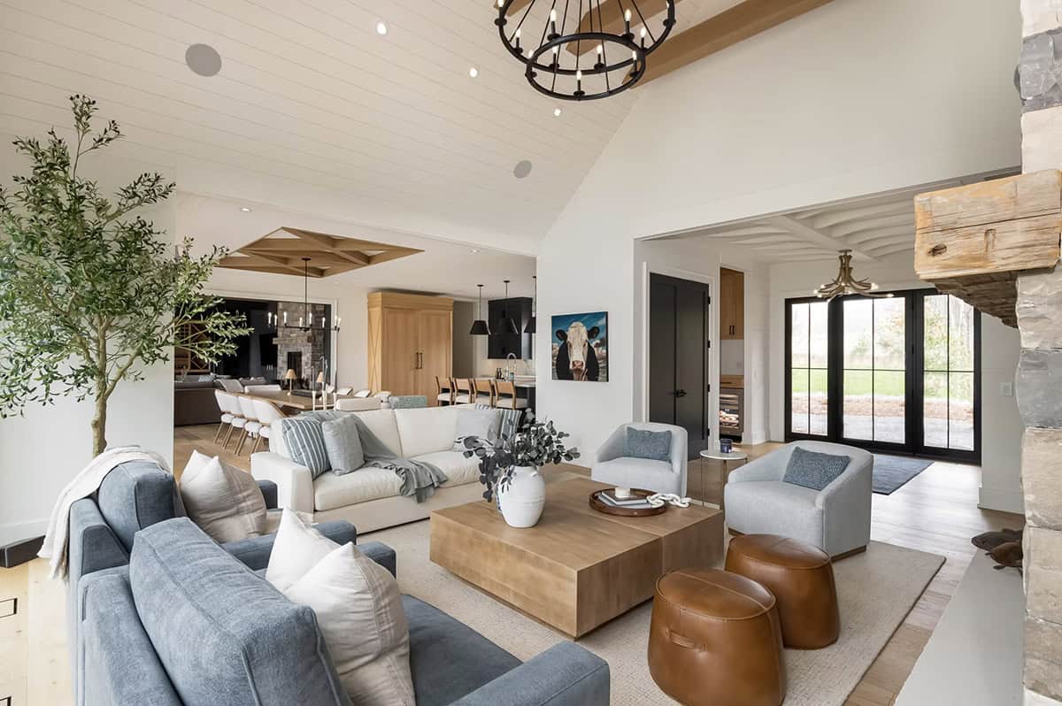 Casual living room flowing into kitchen with blue sofas, wood coffee table, and indoor olive tree