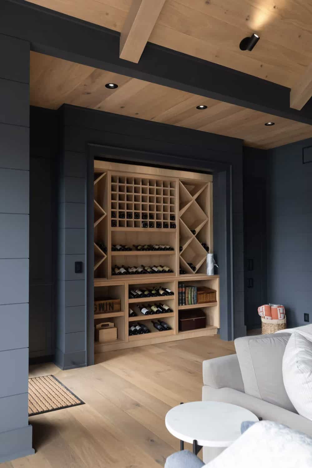 Built-in wine rack in dark-walled lounge nook with cedar ceiling and recessed lighting