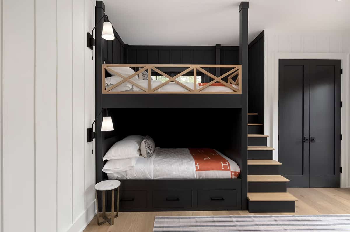 Built-in dark bunk beds with wood guardrail, oak stairs, wall sconces, and under-bed storage drawers