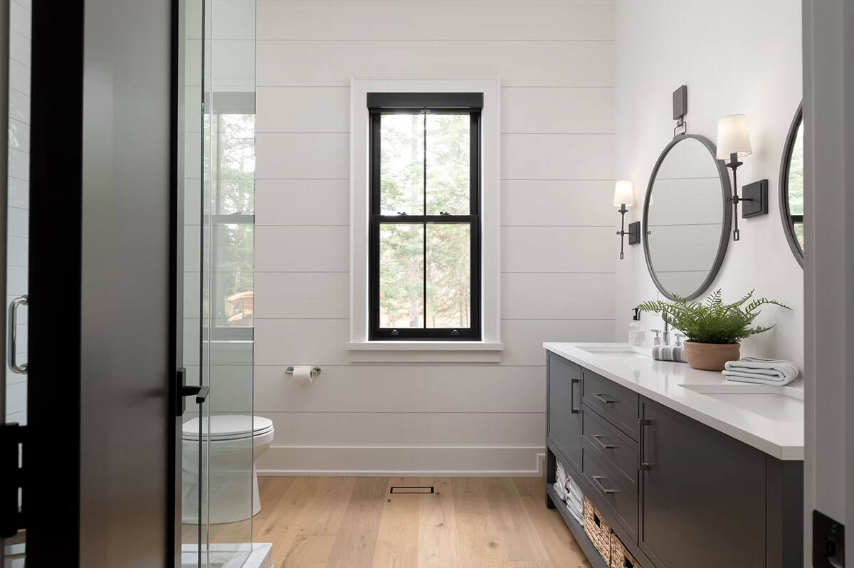 Full guest bathroom with shiplap walls, double vanity, dual round mirrors, glass shower, and black-framed window