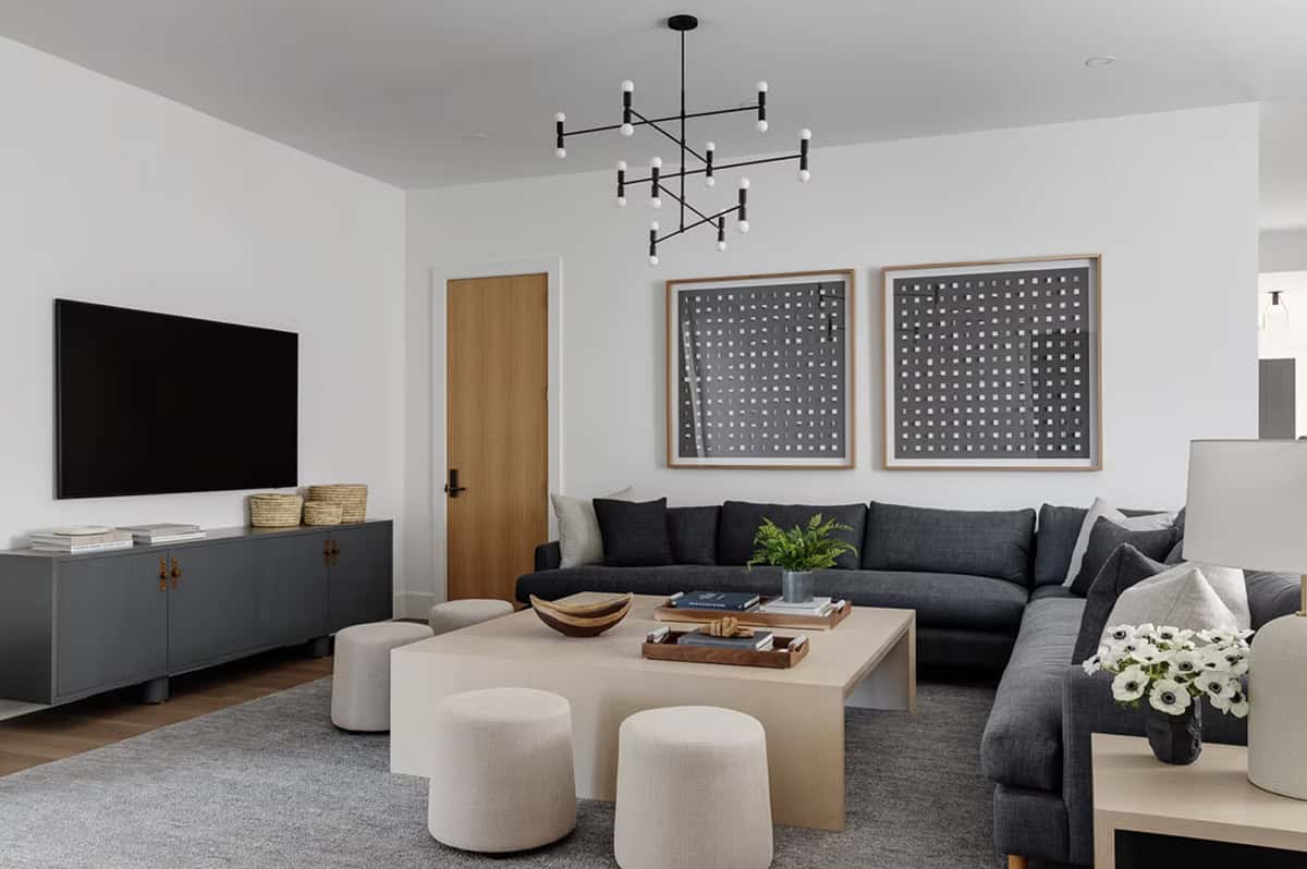 Family room with dark gray sectional sofa, sculptural Sputnik chandelier, woven art panels, and light wood coffee table