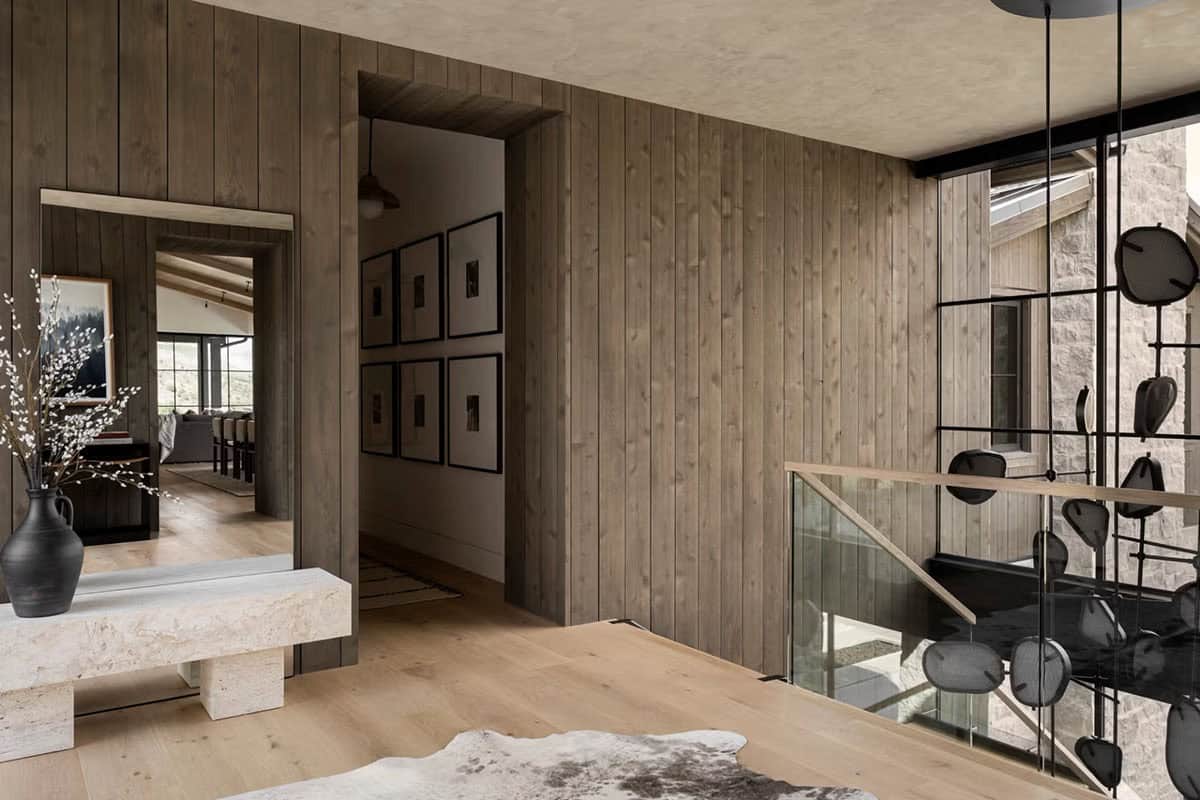 Upper hallway with vertical wood paneling, stone console table, and view to dining room