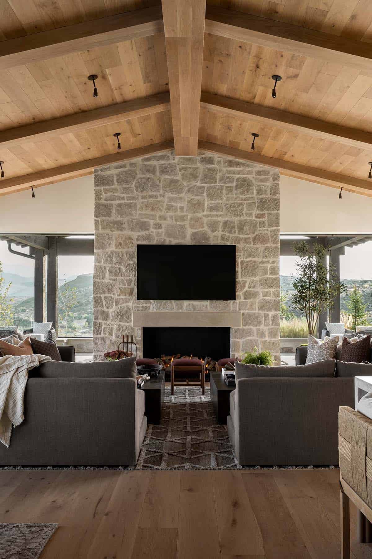 Great room with vaulted wood ceiling, stone fireplace wall, and panoramic mountain views