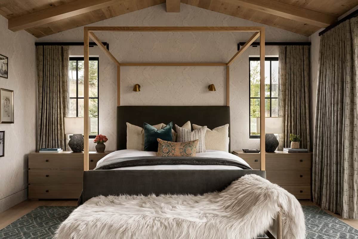 Primary bedroom with four-poster wood canopy bed, vaulted ceiling, and layered textiles