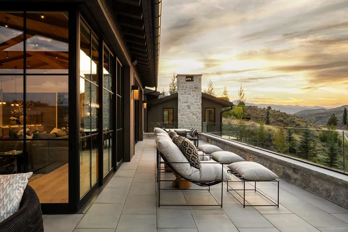Upper terrace with chaise lounges and glass railing overlooking mountain valley at sunset