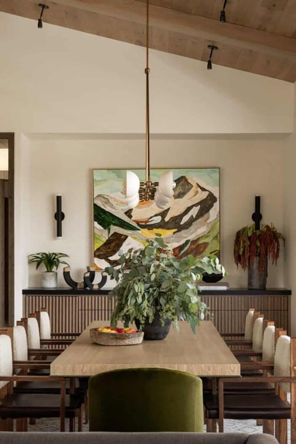 Dining room with large-scale mountain landscape painting and fluted wood sideboard