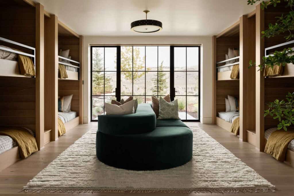 Bunk room with four built-in oak bunk beds, green curved sofa, and black-frame picture window