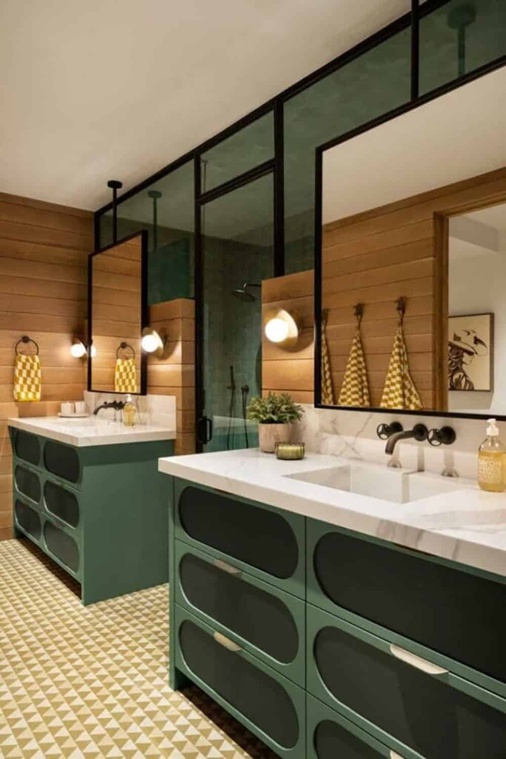 Kids bathroom with forest green dual vanities, geometric patterned floor tile, and glass partition