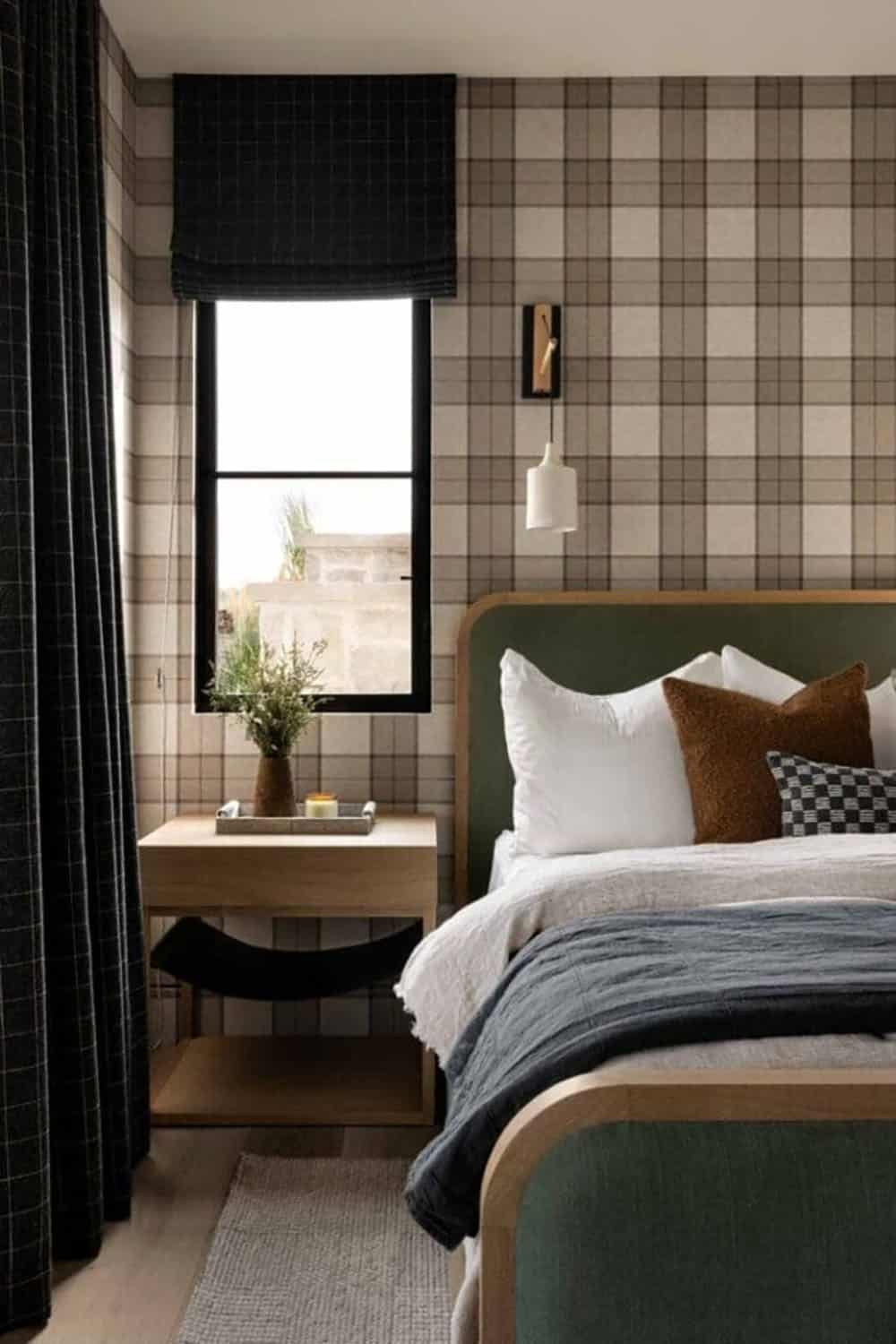 Guest bedroom with plaid wallpaper, green upholstered bed, and dark roman shade