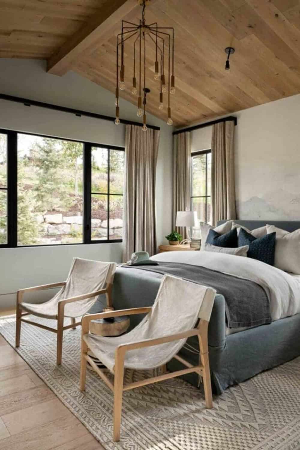 ountertop, and glass shower Guest bedroom with vaulted wood ceiling, canvas sling chairs, blue upholstered bed, and wire chandelier