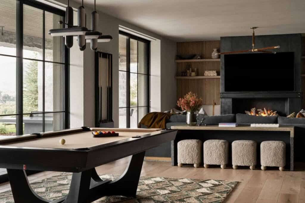 Lower-level game room with pool table, dark fireplace wall, and wood slat built-in shelving