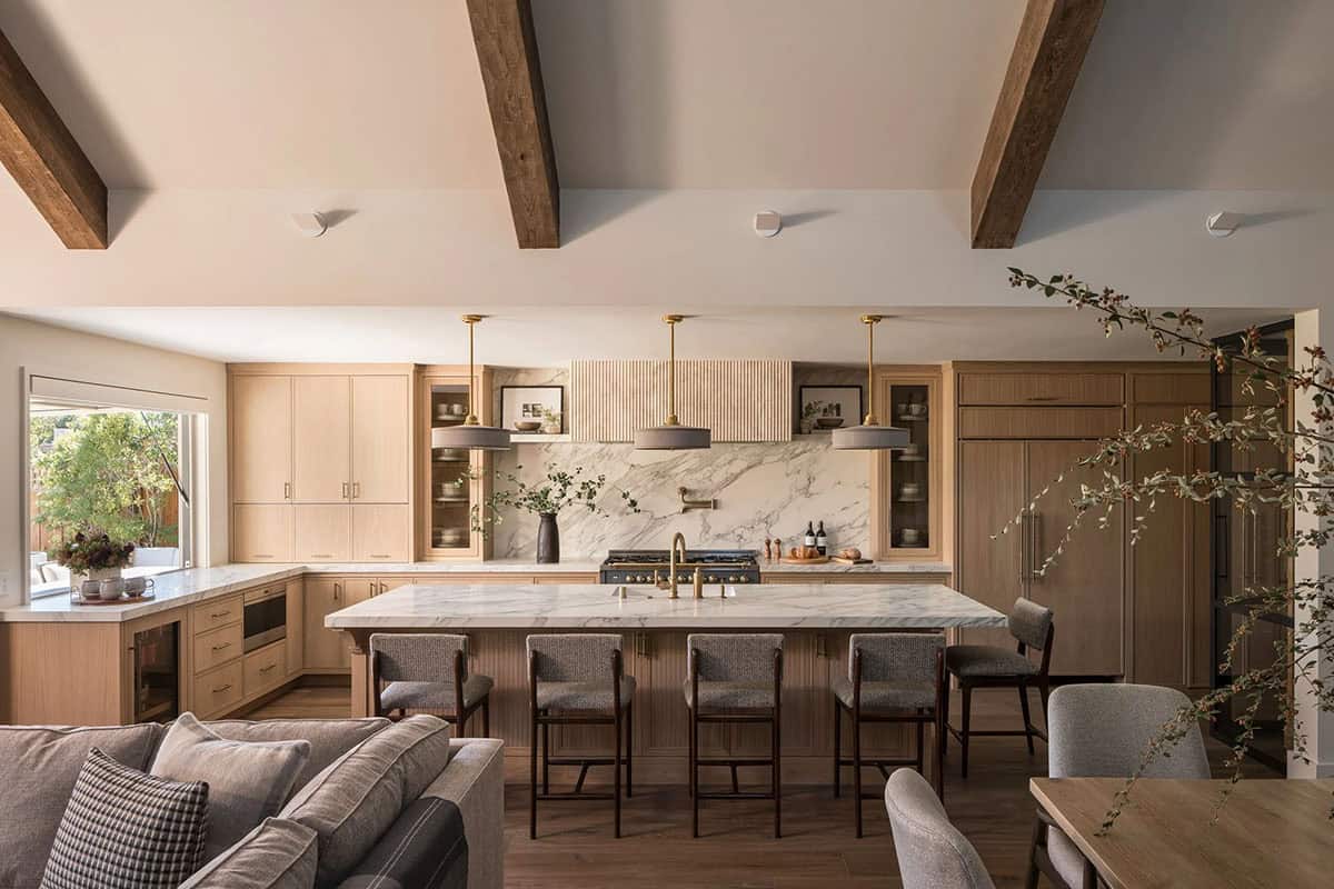 Kitchen with oak cabinets marble island and brass pendants