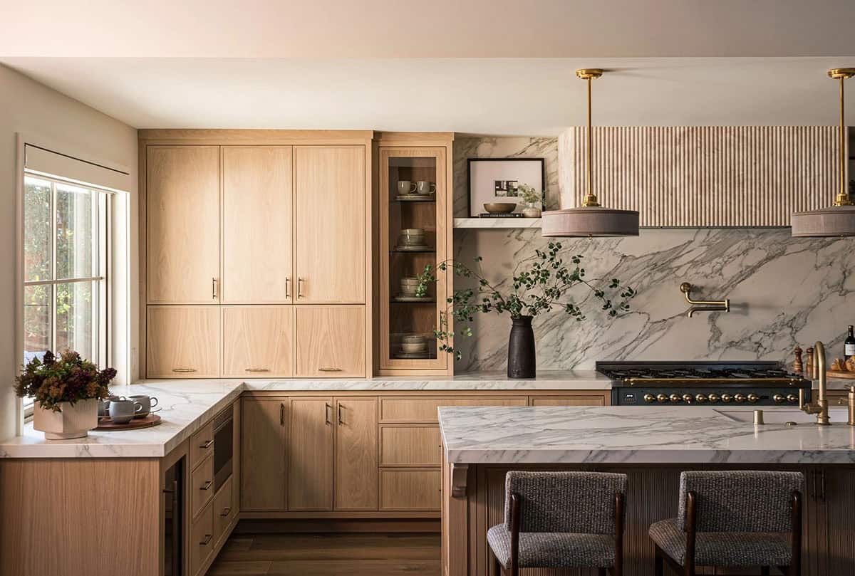 Kitchen with marble backsplash fluted range hood and brass faucet