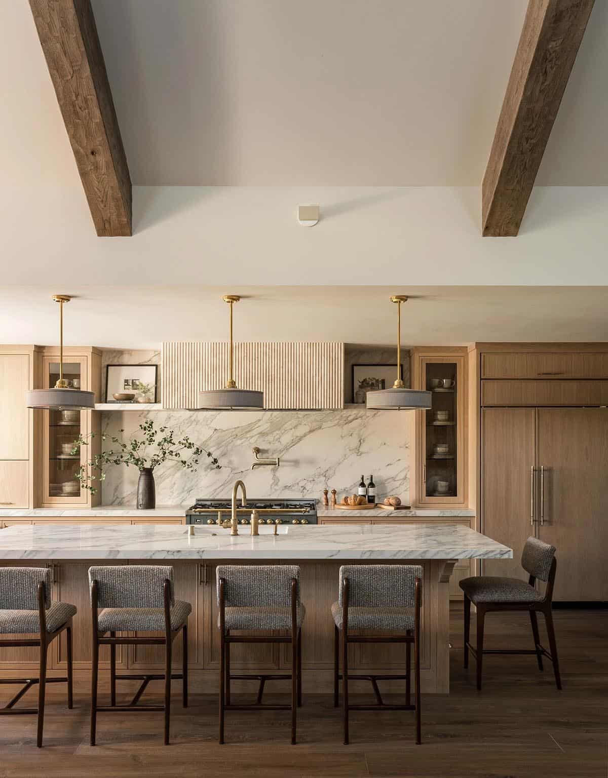 Kitchen island with marble countertop brass pendants and bar stools
