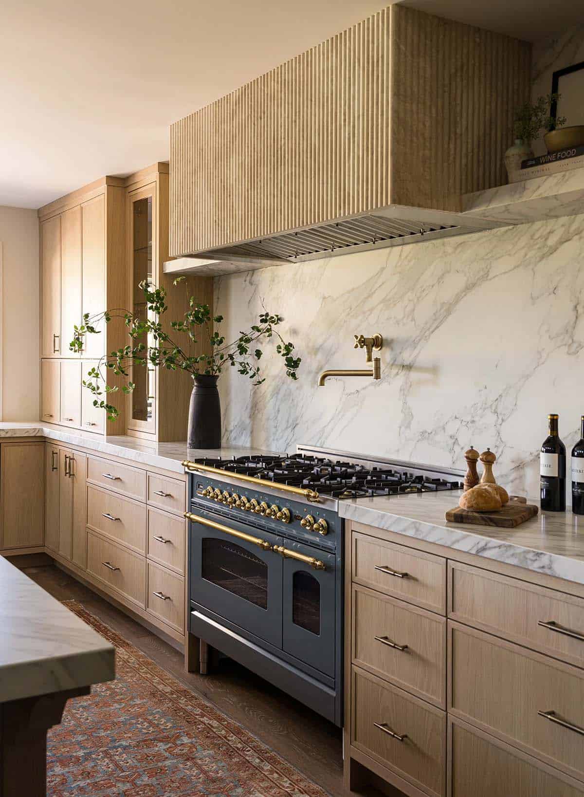 Blue range with brass hardware, marble backsplash and fluted hood