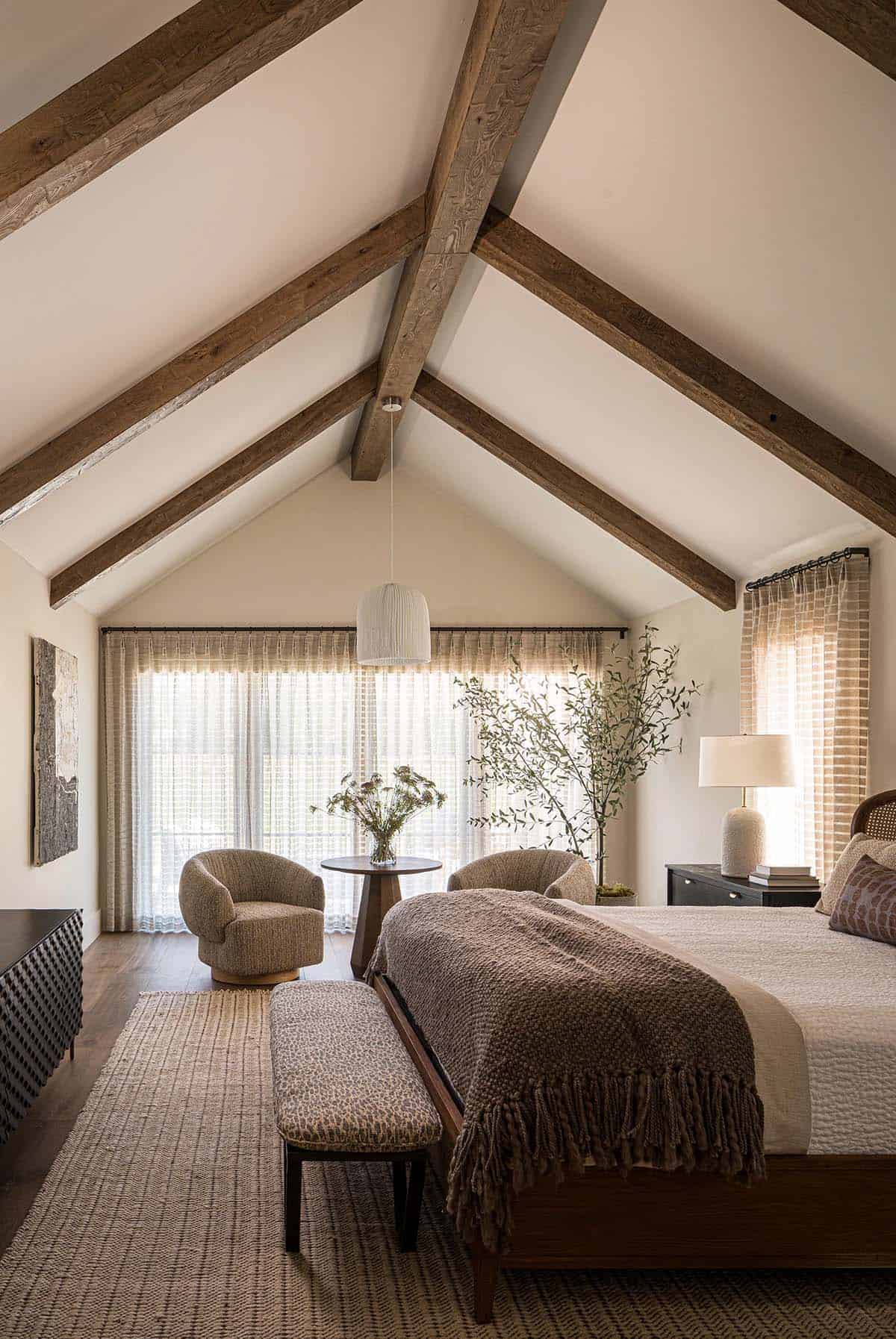 Primary bedroom with vaulted ceiling exposed beams and sitting area