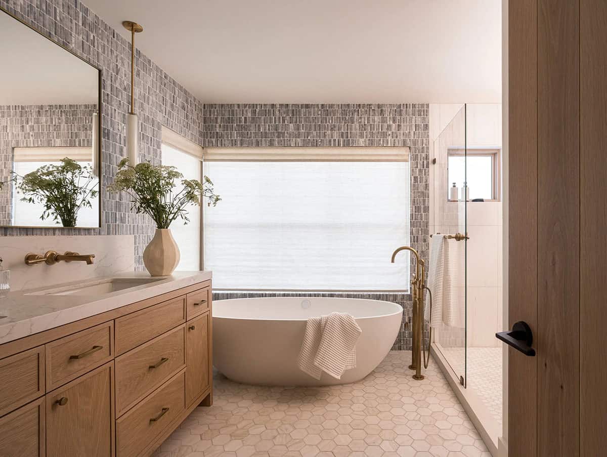 Freestanding soaking tub with hex tile floor and brass fixtures