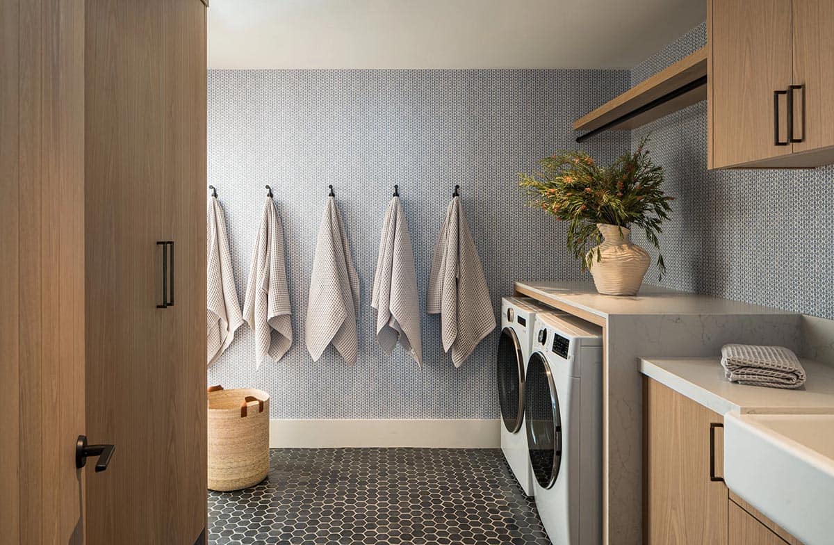 Laundry room with patterned wallpaper hex tile floor and oak cabinetry