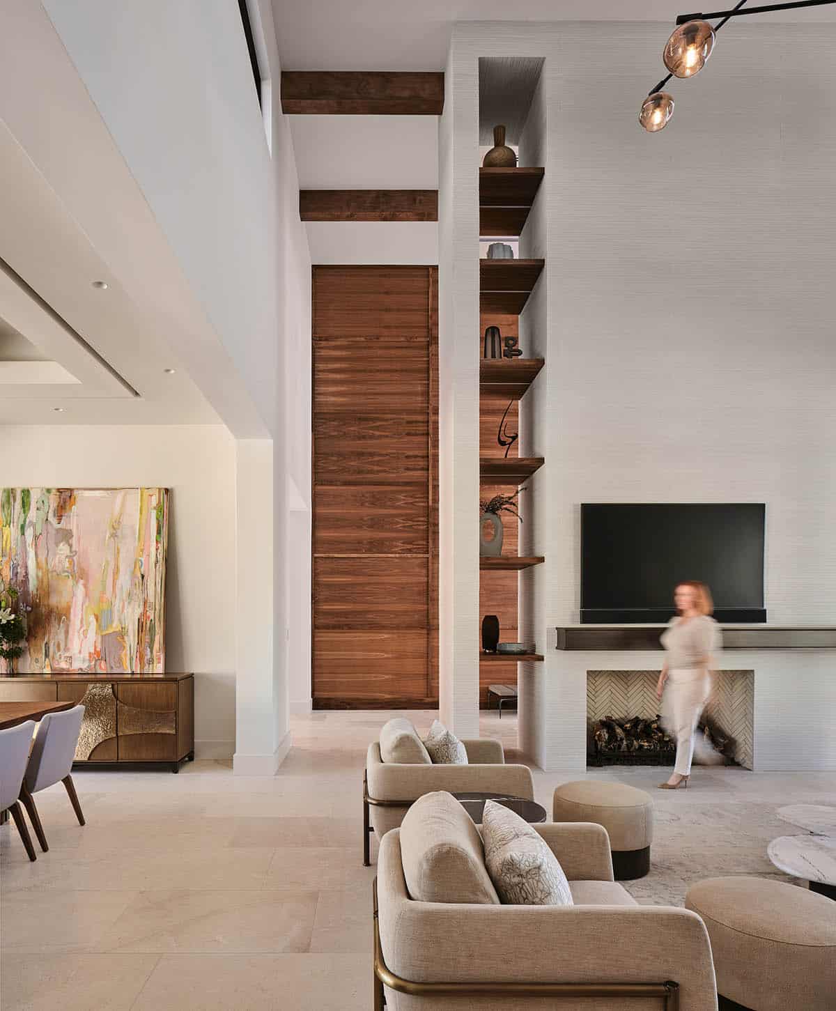 Open plan living room with tall walnut wood accent wall, built-in shelving, fireplace, and dark wood ceiling beams
