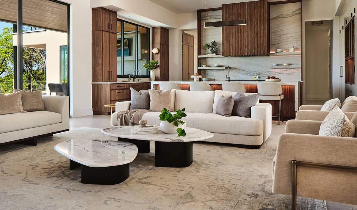 Open plan living and kitchen area with cream sofas, marble coffee tables, walnut cabinetry, and floor-to-ceiling windows