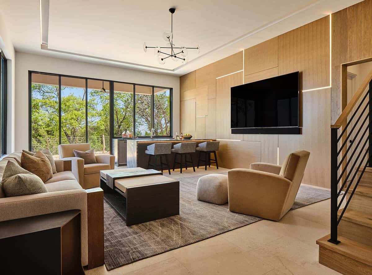 Lower level media room with wood panel TV wall, wet bar, neutral seating, and floor-to-ceiling windows