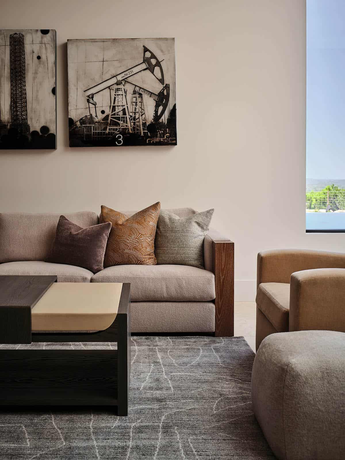 Lower level sitting area with neutral sofa, Texas oil derrick artwork, and dark coffee table