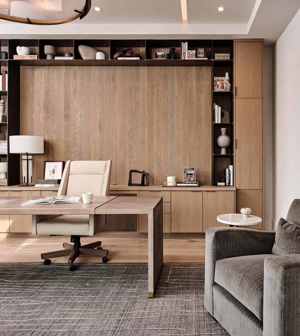 Home office detail with fluted oak wall paneling, built-in shelving, floating desk, and leather task chair