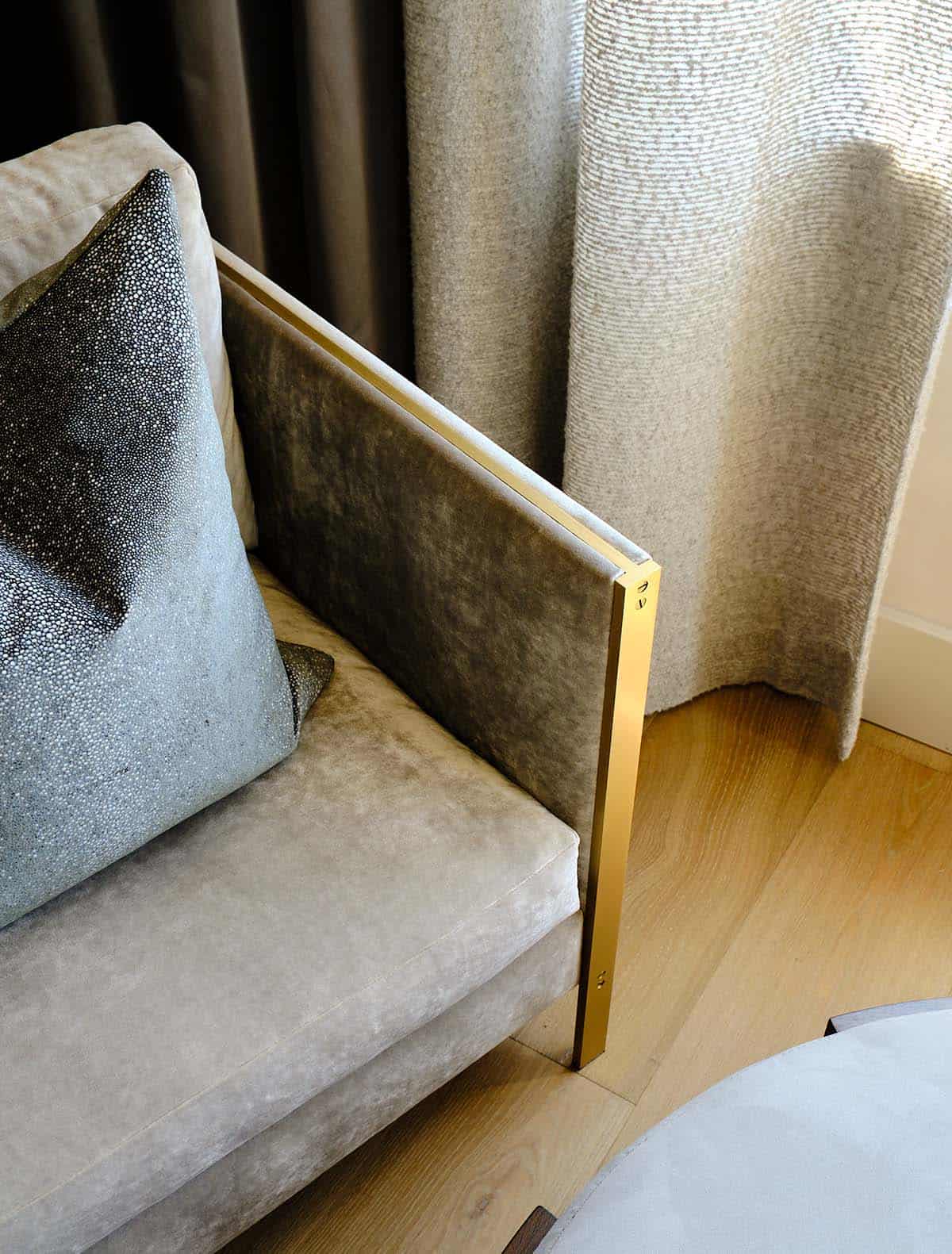 Detail of velvet armchair with brass frame, shagreen pillow, and layered drapery