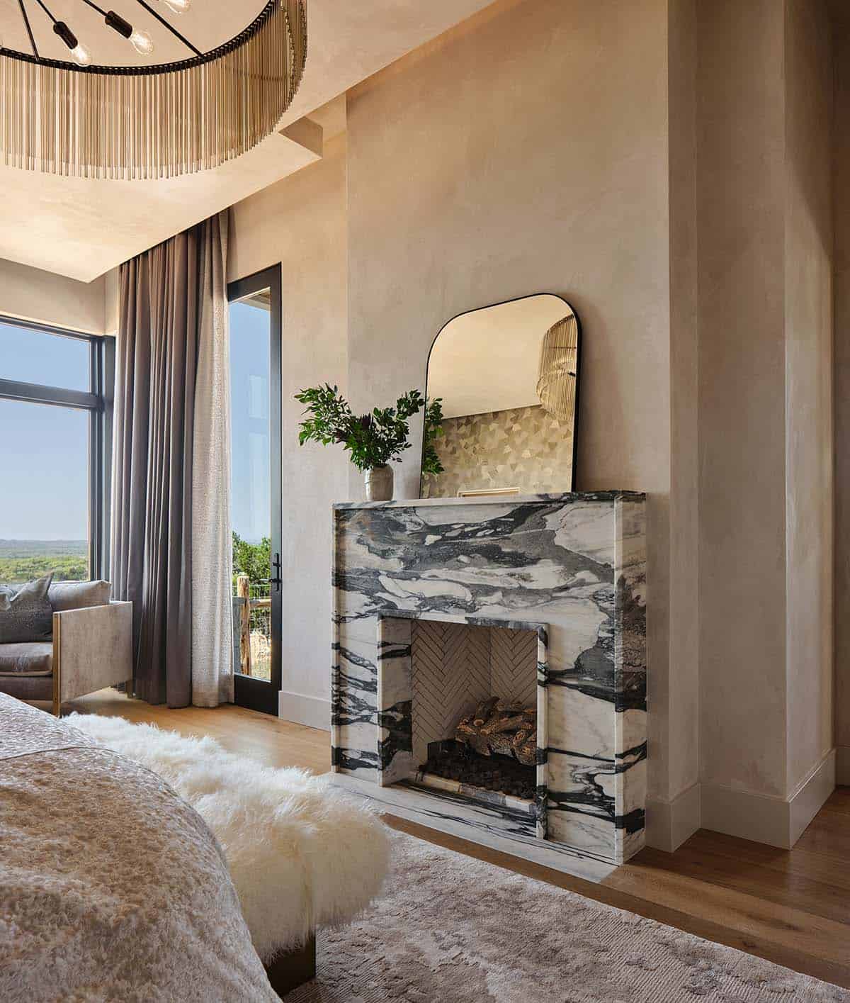 Primary bedroom fireplace with dramatic black and white marble surround, herringbone firebox, and arched mirror